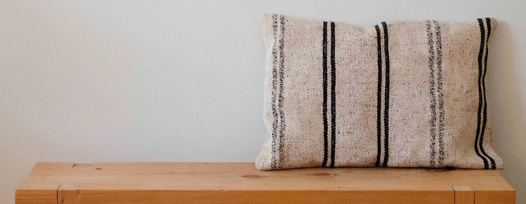 a wooden bench with a striped pillow on it